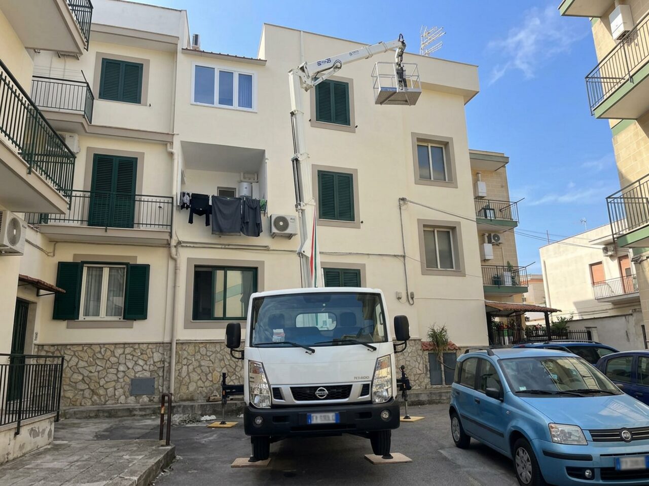 Piattaforma aerea stabilizzata con cestello vuoto davanti a un edificio