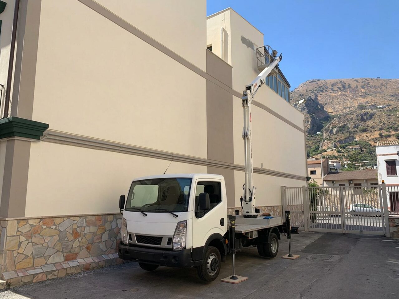 Piattaforma aerea con cestello vuoto accanto a un edificio siciliano